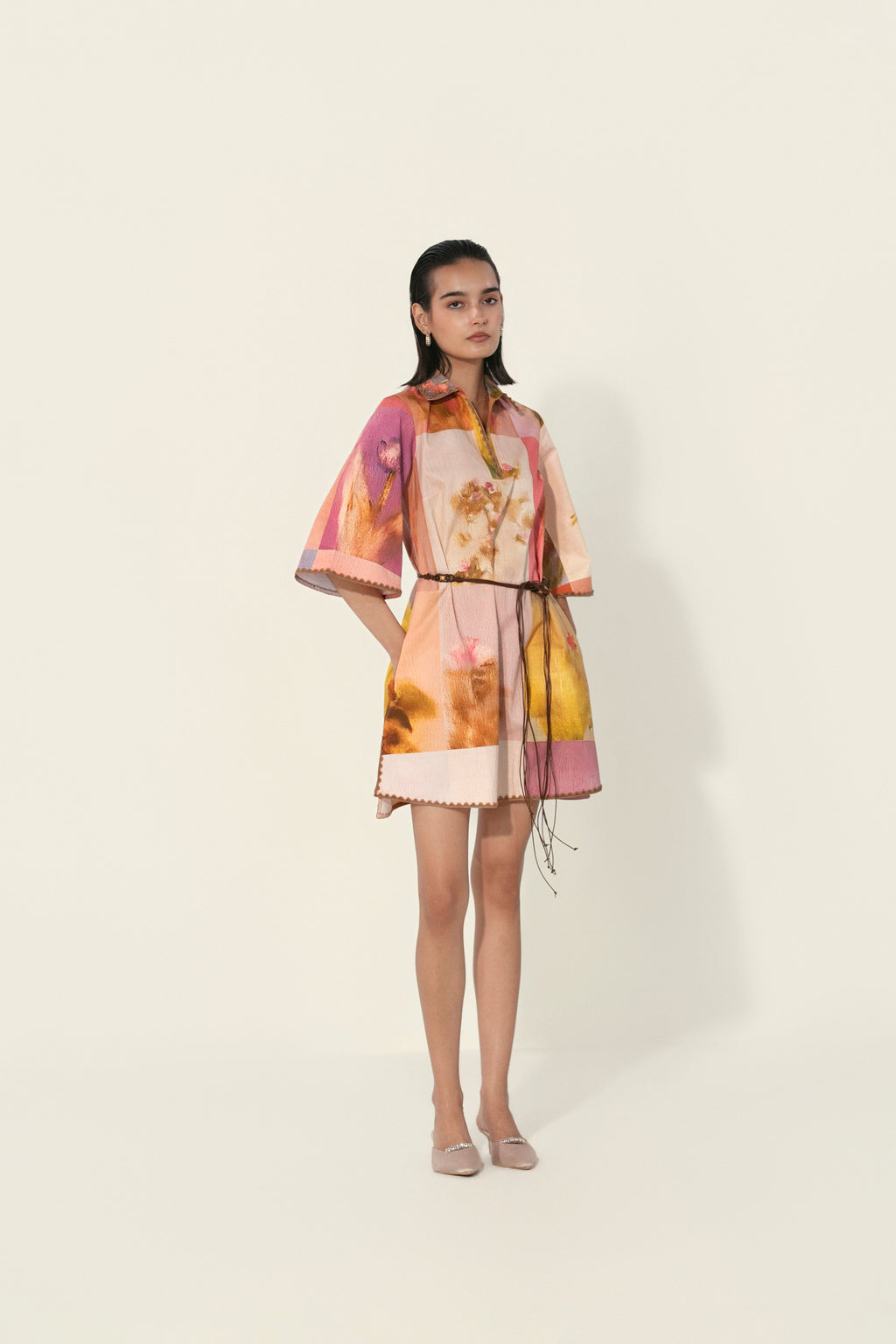 Model wearing a multicolor printed belted mini dress with wide sleeves from Thr3letter premium women's western wear collection.
