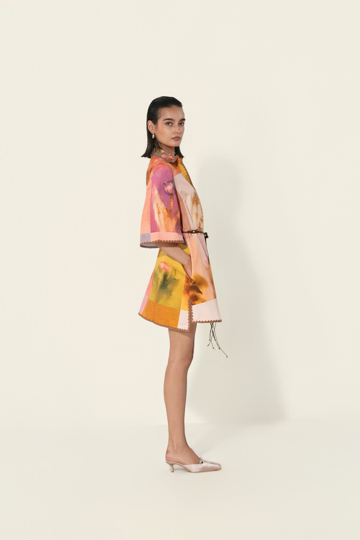 Model wearing a multicolor printed belted mini dress with wide sleeves from Thr3letter premium women's western wear collection.