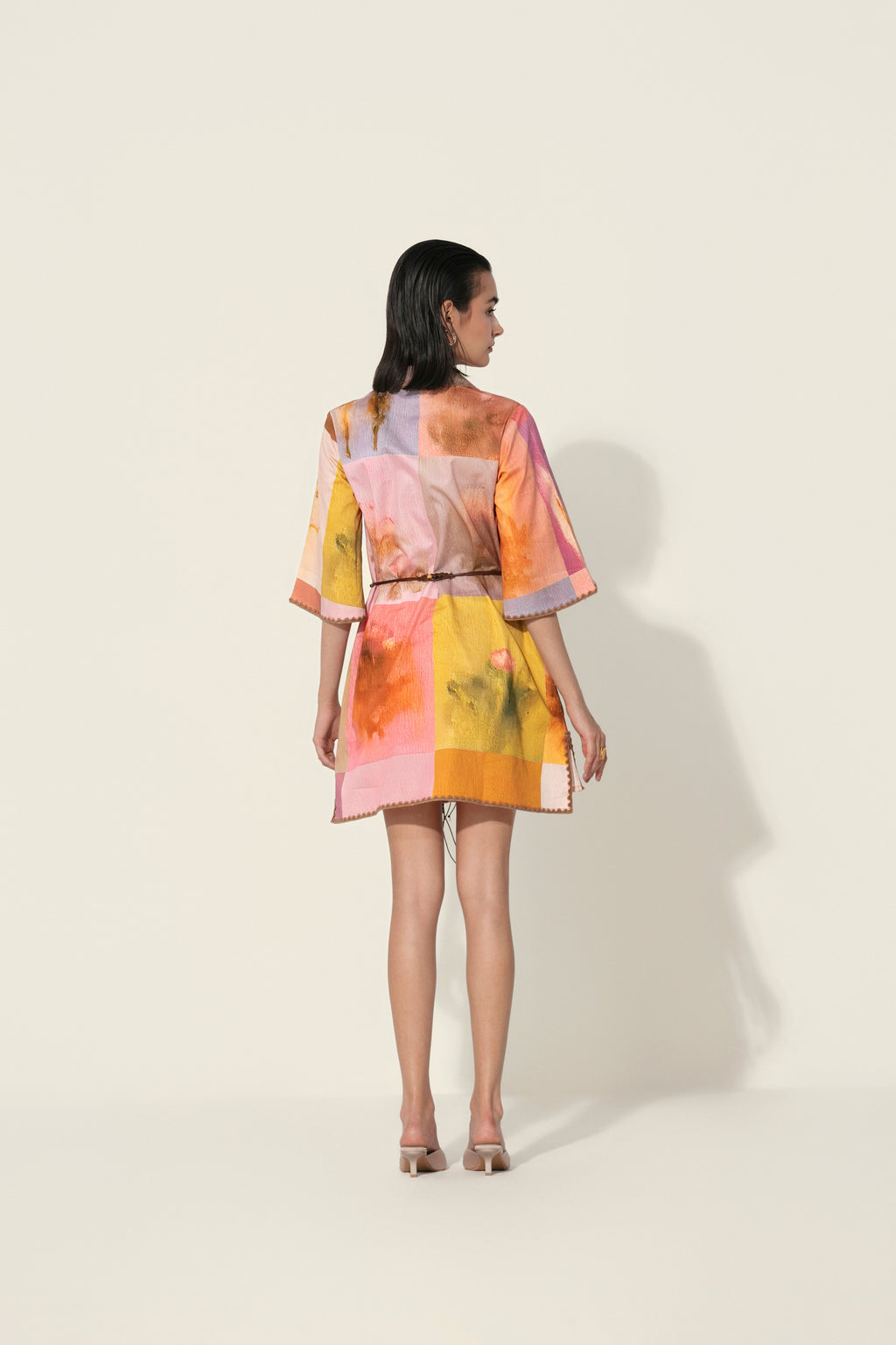 Model wearing a multicolor printed belted mini dress with wide sleeves from Thr3letter premium women's western wear collection.