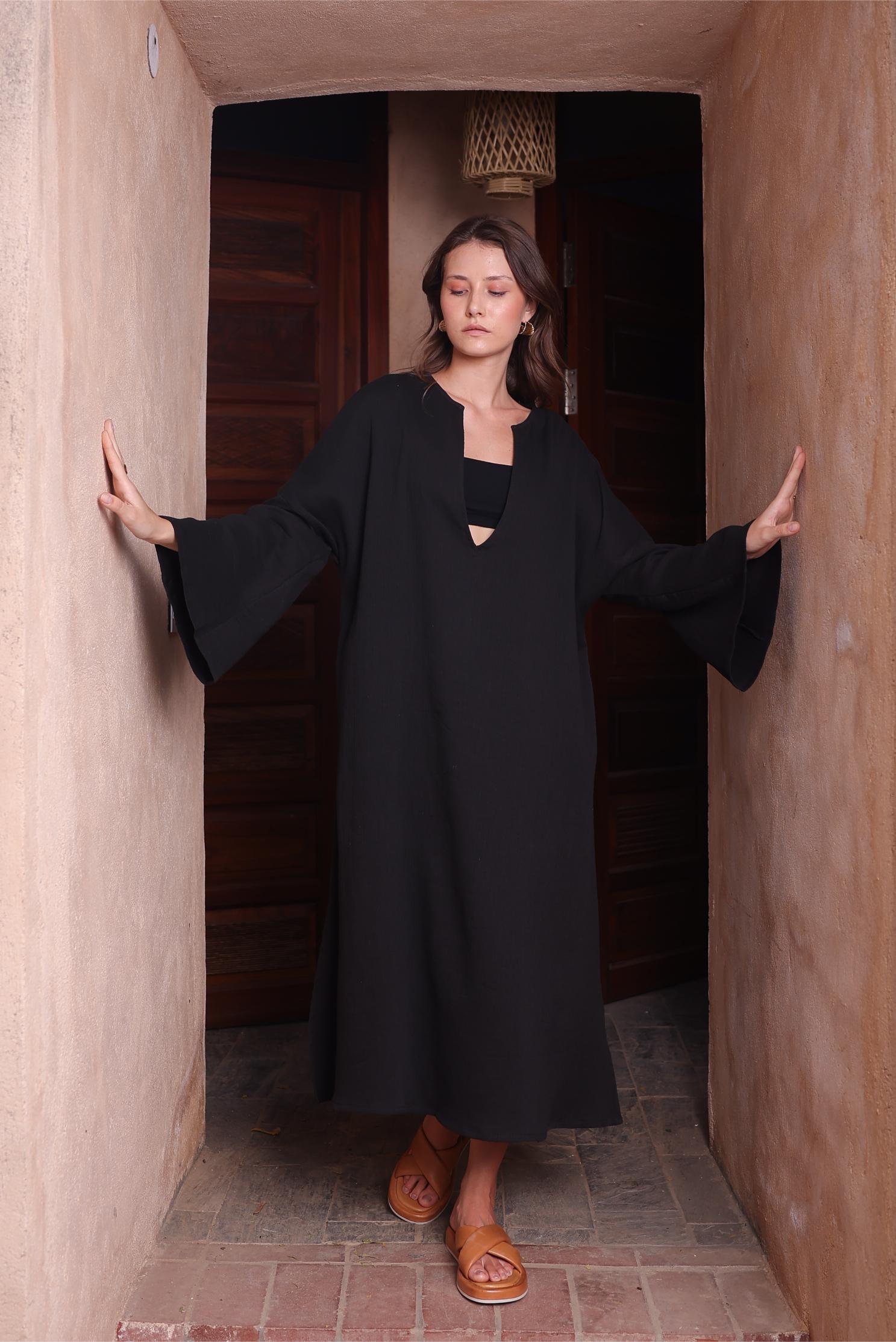 A woman wears Thr3letter's Kiaan Kaftan in a rich black shade, exuding an air of sophistication.