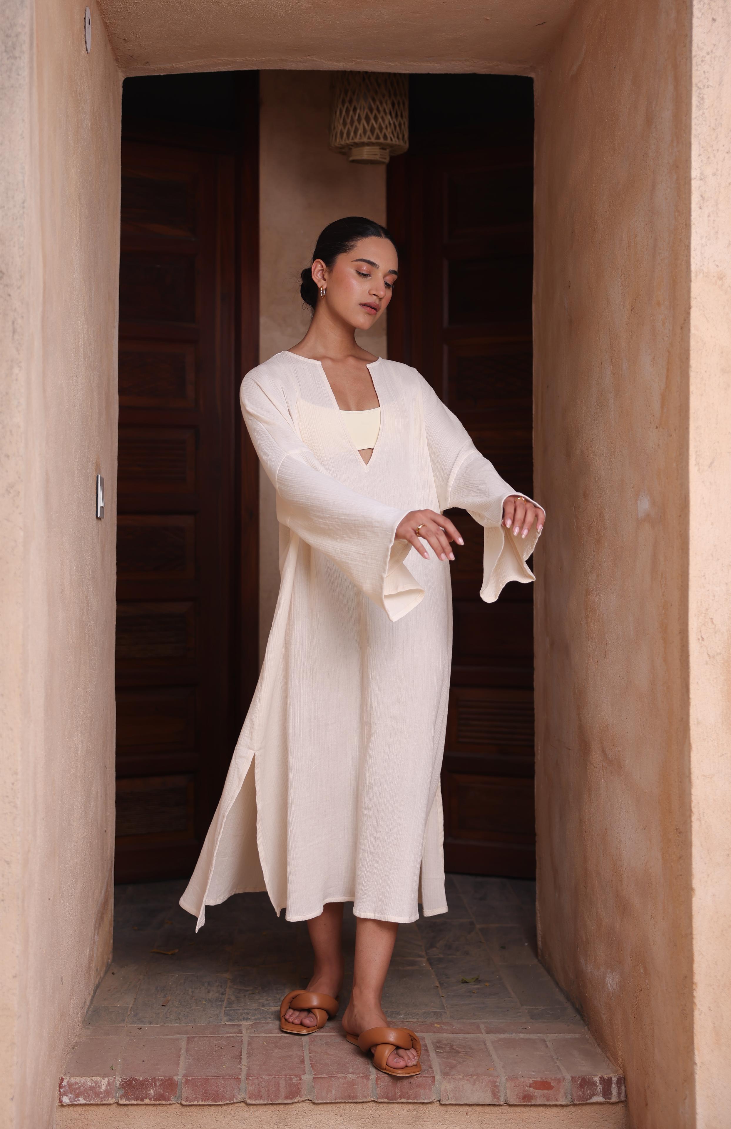 A woman wears Thr3letter's Kiaan Kaftan in a warm almond shade, creating a serene, tranquil atmosphere.