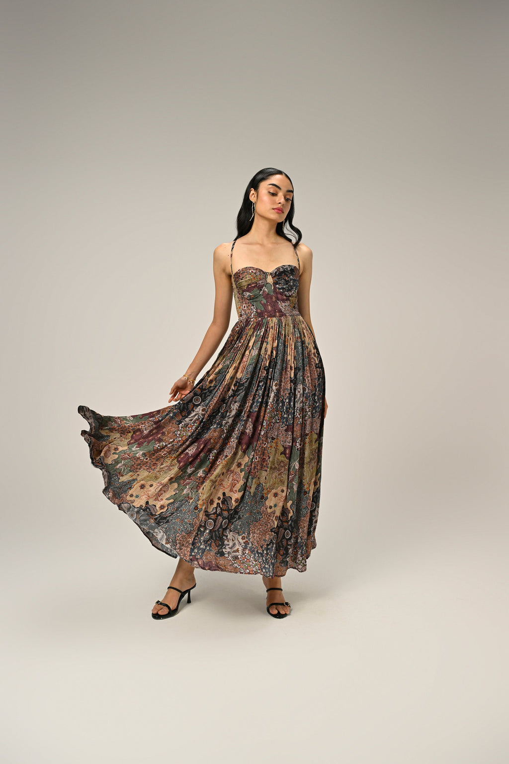Woman posing in a vintage paisley bustier maxi dress featuring a pleated skirt and lightweight fabric.